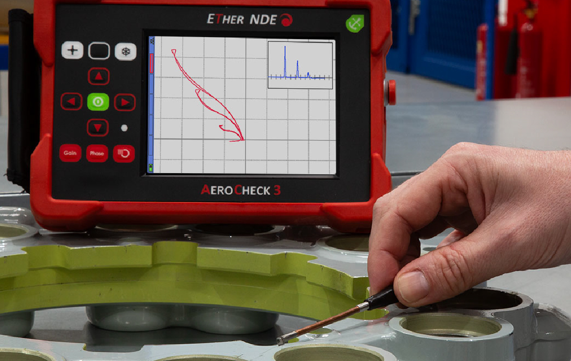 AeroCheck 3 eddy current flaw detector in use with a pencil probe on a metal testing surface